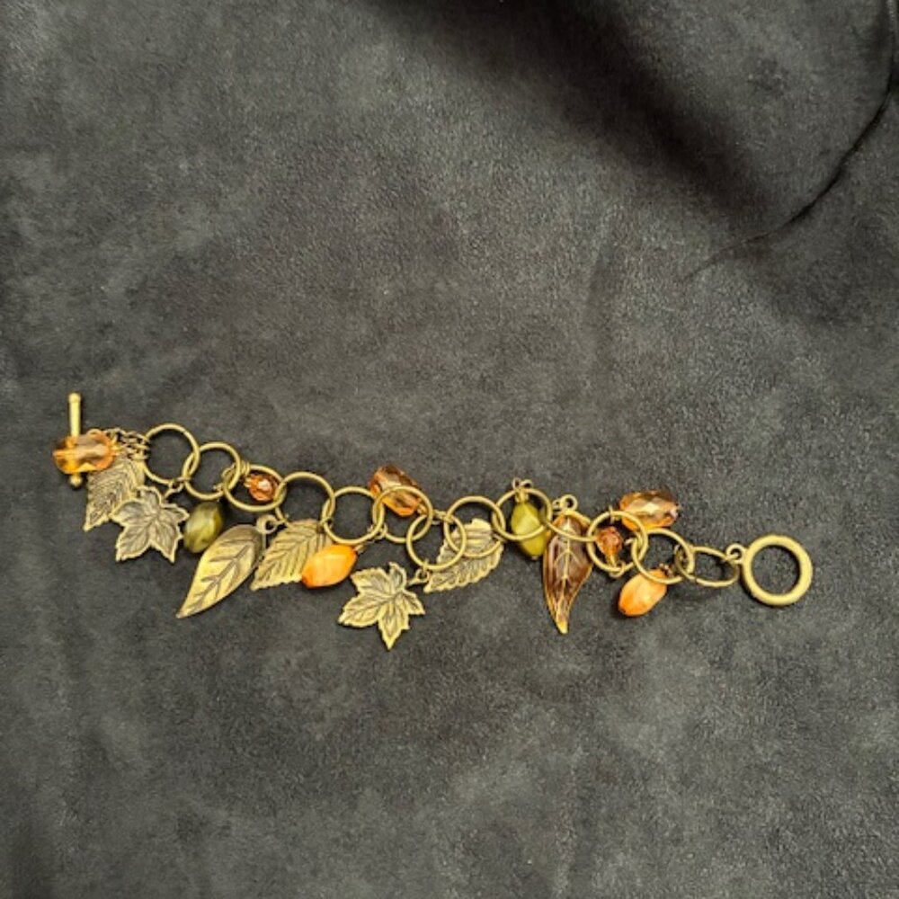 Bracelet of large circle chain with orange and green beads plus metal leaves.